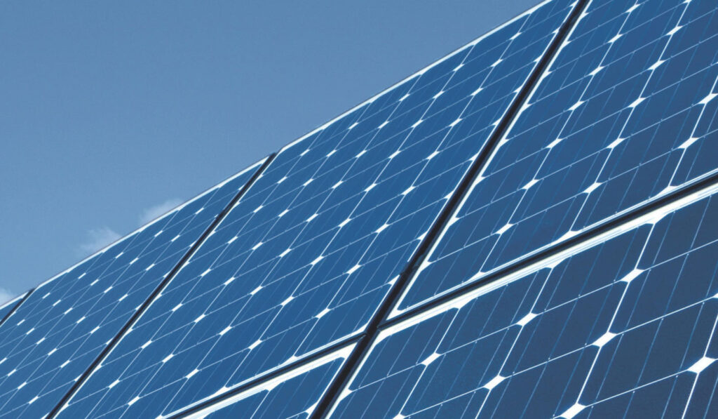Solarmodule mit blauem Himmel im Hintergrund, Sonnenstrahlen reflektieren auf der glänzenden Oberfläche.